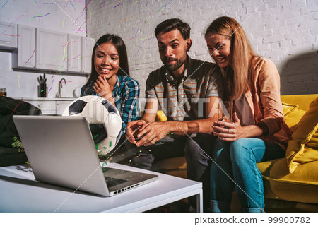 Happy friends of football fans watching soccer on laptop Happy friends of football fans watching soccer on laptop 99900782