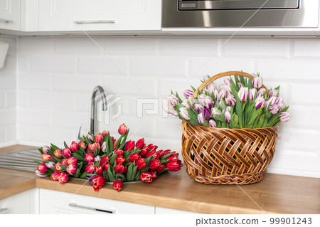 A large number of tulips of different colors lies on the table in the kitchen. Flowers in the sink A large number of tulips of different colors lies on the table in the kitchen. Flowers in the sink 99901243