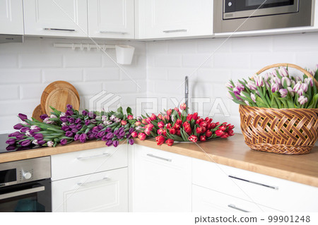A large number of tulips of different colors lies on the table in the kitchen. Flowers in the sink 99901248