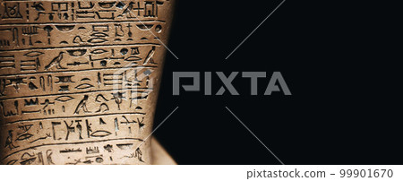 A stone tablet engraved with ancient Egyptian hieroglyphic symbols against a dark black background with copy space 99901670