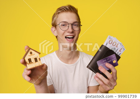 Financing Home Purchase Concept. A happy young man holds in his hands a wallet with money and a credit card to buy his home. High quality photo Financing Home Purchase Concept. A happy young man holds in his hands a wallet with money and a credit card to buy his home. High quality photo 99901739