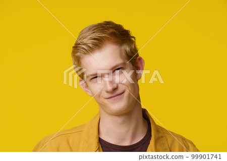 Emotion of Cunning and Deception Concept. A European Young Man shows an Emotion of Cunning and Distrust on a Yellow Background. High quality photo 99901741