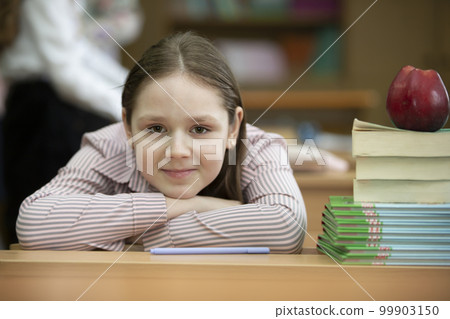 The schoolgirl laid her head on the desk. Girl in the classroom with books and an apple. Back to school. 99903150