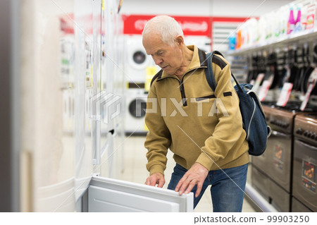 senor man pensioner buying fridge in showroom of electrical appliance store 99903250