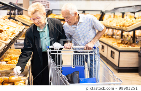 mature european couple shopping buns and bread in bakery section of supermarket 99903251