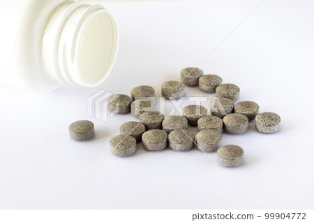 Round brown tablets with spots on a white background scattered near the jar. Iron supplements. Health medications 99904772