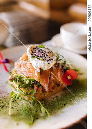 Salmon on a pillow of tomato on toast, and a poached egg on top, garnished with black sesame, spirulina and microgreens Salmon on a pillow of tomato on toast, and a poached egg on top, garnished with black sesame, spirulina and microgreens 99906183