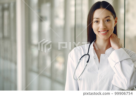 Woman in a uniform. Doctio with a stethoscope. Brunette in a hall. Woman in a uniform. Doctio with a stethoscope. Brunette in a hall. 99906754