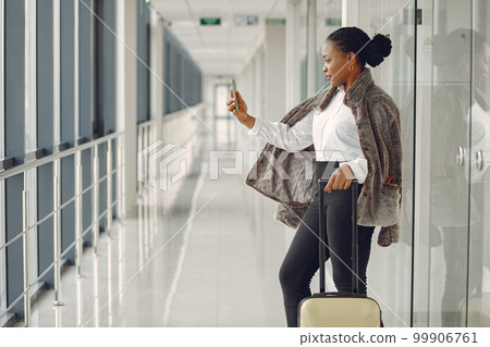 Black woman at the airport. Girl with suitcase. Lady in a white shirt. Black woman at the airport. Girl with suitcase. Lady in a white shirt. 99906761