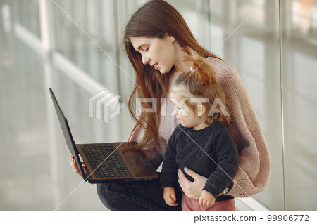 Mother with daughter. Family in hall. Woman in a pink sweater. Family use the laptop. Mother with daughter. Family in hall. Woman in a pink sweater. Family use the laptop. 99906772