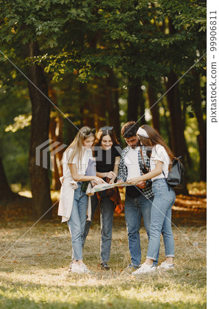 Adventure, travel, tourism, hike and people concept. Group of smiling friends in a forest. Man with binocularus. 99906811