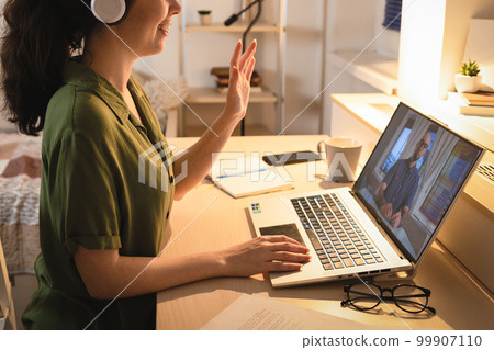 Close up of Caucasian young woman wearing headphones videocalling using laptop. Student learning in home. Concept of remote work and freelance Close up of Caucasian young woman wearing headphones videocalling using laptop. Student learning in home. Concept of remote work and freelance 99907110