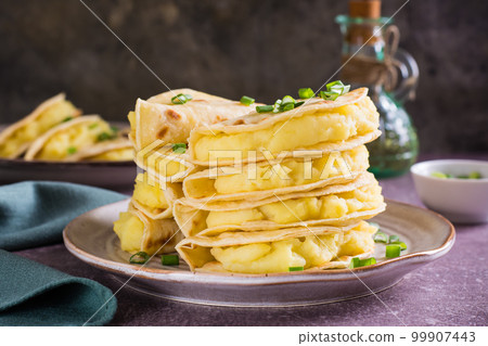 Kystyby - a thin flatbread filled with mashed potatoes and onions on a plate on the table. Kystyby - a thin flatbread filled with mashed potatoes and onions on a plate on the table. 99907443