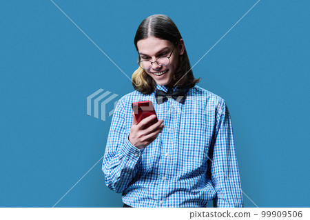 Young smart male looking into smartphone on blue studio background 99909506