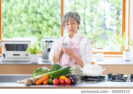 Smiling senior woman standing in the kitchen Smiling senior woman standing in the kitchen 99909535