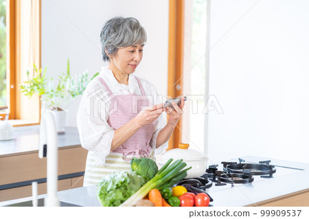 Smiling senior woman standing in the kitchen Smiling senior woman standing in the kitchen 99909537