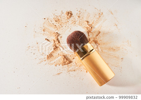 Soft cosmetic brush, with shining sparkling powder on the bristles.The powder is scattered on the table, on a light background with space to copy in the concept of beauty and makeup.High quality photo 99909832