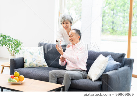 Senior couple with smartphones in the living room 99909869