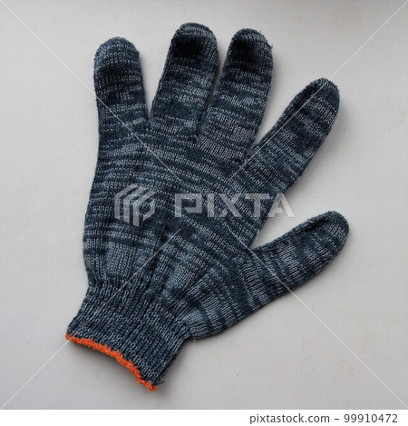 fabric glove made of gray-blue cotton material isolated on a light surface, one protective glove made of soft fabric lying on a plane close-up fabric glove made of gray-blue cotton material isolated on a light surface, one protective glove made of soft fabric lying on a plane close-up 99910472