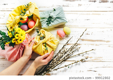 Wrapping a gift in eco friendly reusable fabric package 99912802