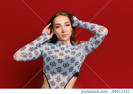 Confident young woman with her hands behind head on red background Confident young woman with her hands behind head on red background 99913332