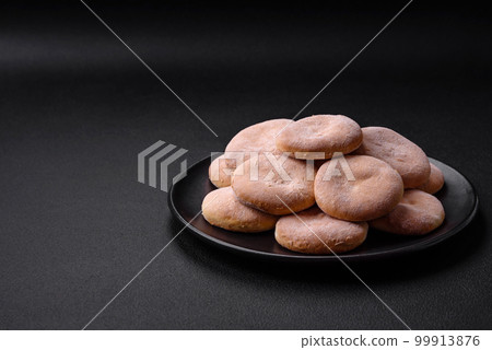 Delicious fresh baked cornmeal shortcakes or cookies on a black plate 99913876
