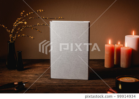 Hard cover book mock up on wooden table. Night interior with candles, plant and coffee. 3D rendering Hard cover book mock up on wooden table. Night interior with candles, plant and coffee. 3D rendering 99914934