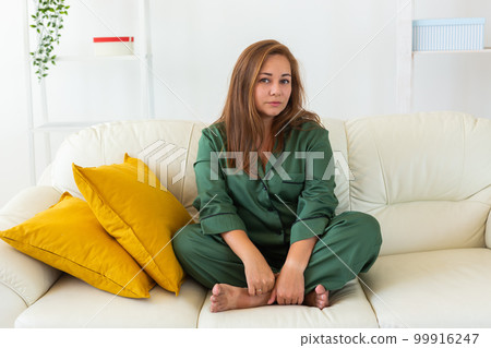 Cute female model in pajama enjoying morning. Pleasant woman sitting on sofa. Good mood 99916247