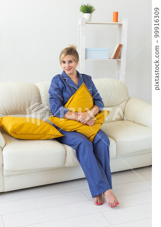 Fun minded woman wear pajama she sitting on couch use rest relax spend time in living room lounge home in own room hotel wake up 99916309