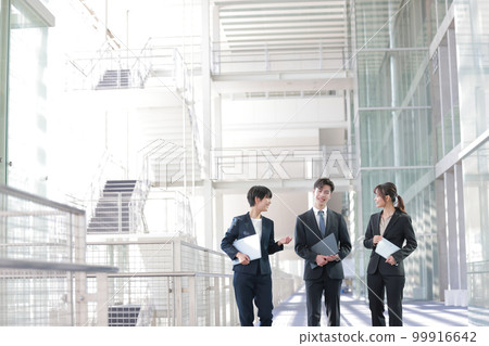 Three business people talking while walking with a device_6 Three business people talking while walking with a device_6 99916642