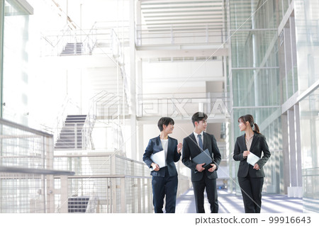 Three business people talking while walking with a device_7 99916643