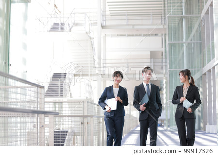Three business people smiling while holding devices_1 Three business people smiling while holding devices_1 99917326