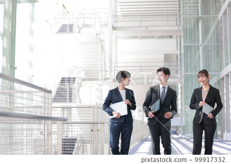 Three business people holding a device and talking with a smile_4 Three business people holding a device and talking with a smile_4 99917332