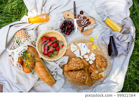 Picnic in the field with berries, juice, cheese, sausage and sweet croissants Picnic in the field with berries, juice, cheese, sausage and sweet croissants 99922164
