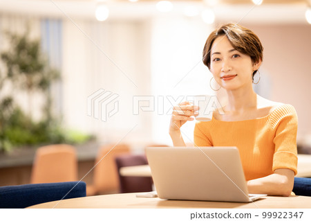 Middle woman using a laptop drinking coffee Middle woman using a laptop drinking coffee 99922347