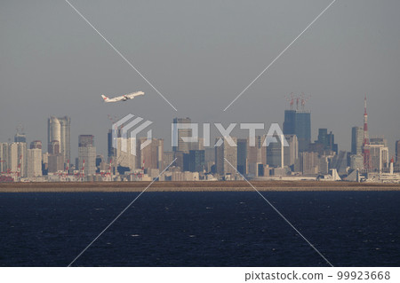 An airplane taking off with Tokyo skyscrapers in the background An airplane taking off with Tokyo skyscrapers in the background 99923668