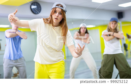 Young girl in cap training breakdance Toprock moves in dance hall 99925212