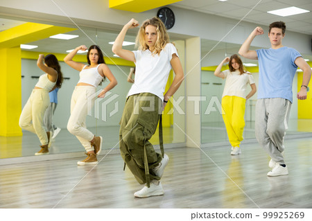Dancer boys and girls showing different tricks and movements while dancing in studio, flexible and sportive female on floor Dancer boys and girls showing different tricks and movements while dancing in studio, flexible and sportive female on floor 99925269