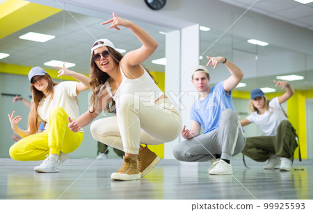 Young girl sitting in breakdance pose in dance hall 99925593
