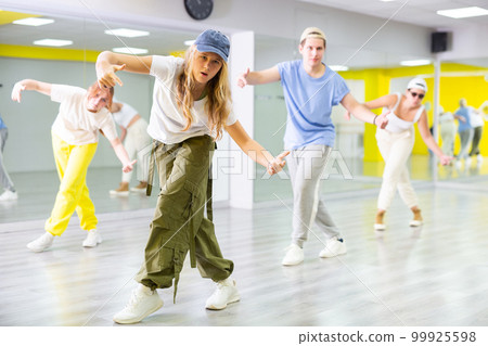 Teenage girl in cap training breakdance Toprock moves in dance hall Teenage girl in cap training breakdance Toprock moves in dance hall 99925598
