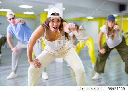 Young girl in cap training breakdance Toprock moves in dance hall 99925659