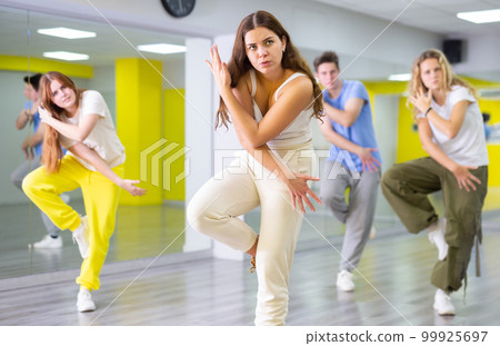 Active talented performing dance elements during lesson in modern fitness studio with mirrors 99925697