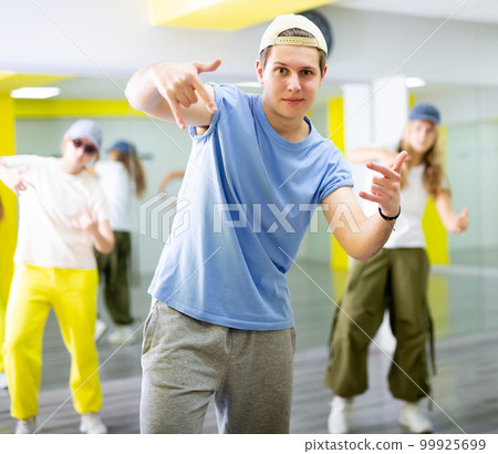Expressive teenage boy dancer having group training in dance hall 99925699