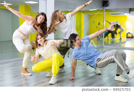 Group portrait of cheerful, talented and active tween dancers in casual clothes posing together in fitness studio 99925701