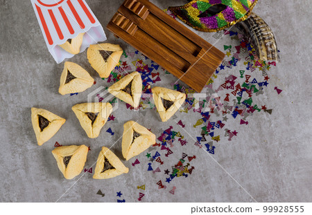 Purim celebrations with hamantaschen cookies shofar noisemakers, tallit carnival masks are symbols of Jewish holiday 99928555