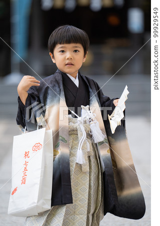 身著日服前來參拜七五山神社的5歲小孩手持扇子站在神社本殿的背景下的照片（特寫） 99929549
