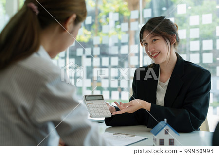 Guarantee, mortgage, contract, contract, signed, real estate agent or bank officer holding a calculator, submits a bid with a customer to buy a home before signing to make a deal. Guarantee, mortgage, contract, contract, signed, real estate agent or bank officer holding a calculator, submits a bid with a customer to buy a home before signing to make a deal. 99930993