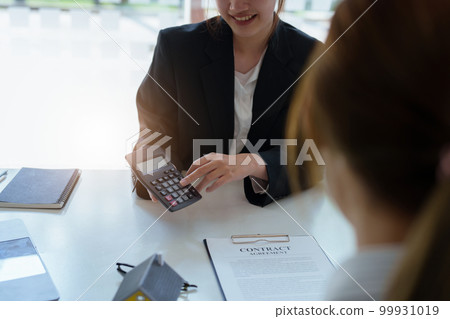 Guarantee, mortgage, contract, contract, signed, real estate agent or bank officer holding a calculator, submits a bid with a customer to buy a home before signing to make a deal. 99931019
