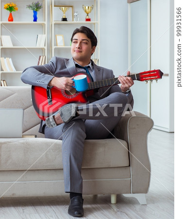 Businessman playing guitar at home Businessman playing guitar at home 99931566
