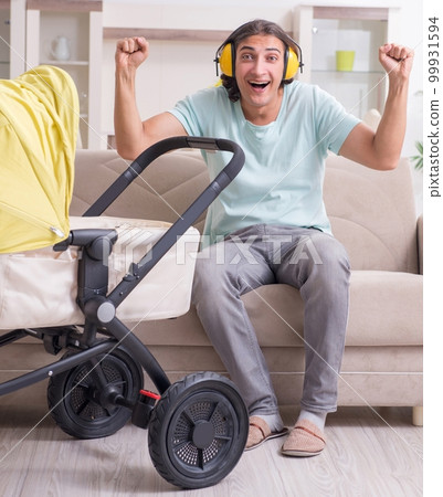 Young man looking after baby in pram 99931594